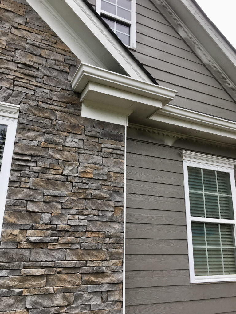 Close up of house paint modern gray hardiboard and stacked stone