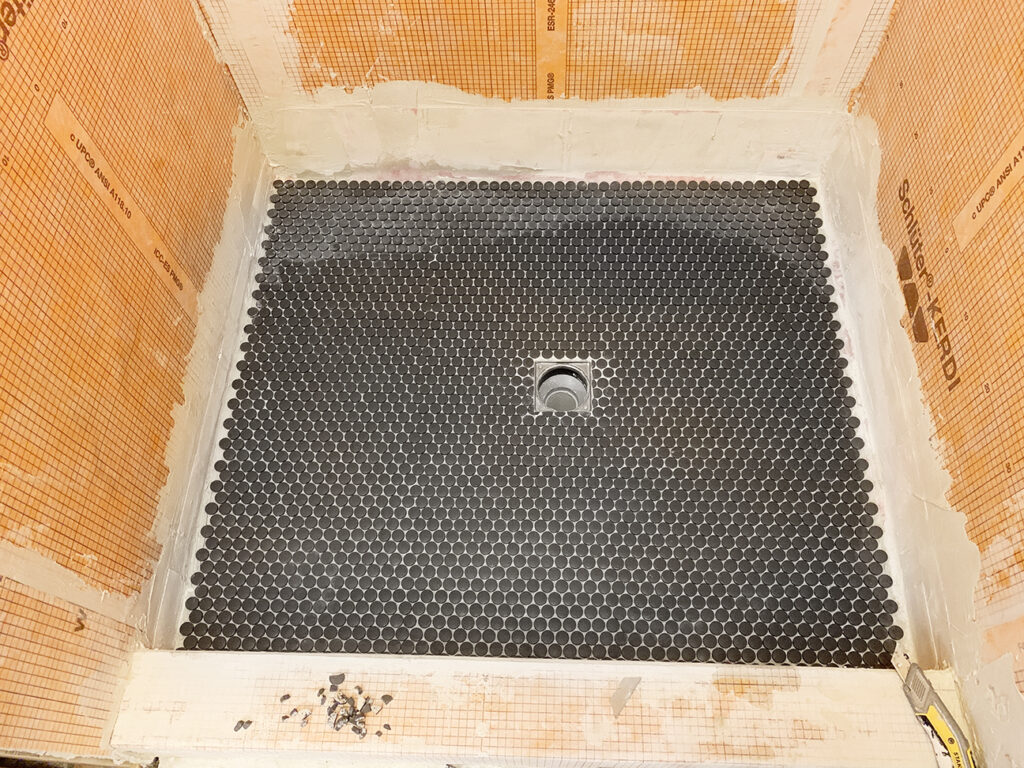 installed gray penny tile in the shower floor