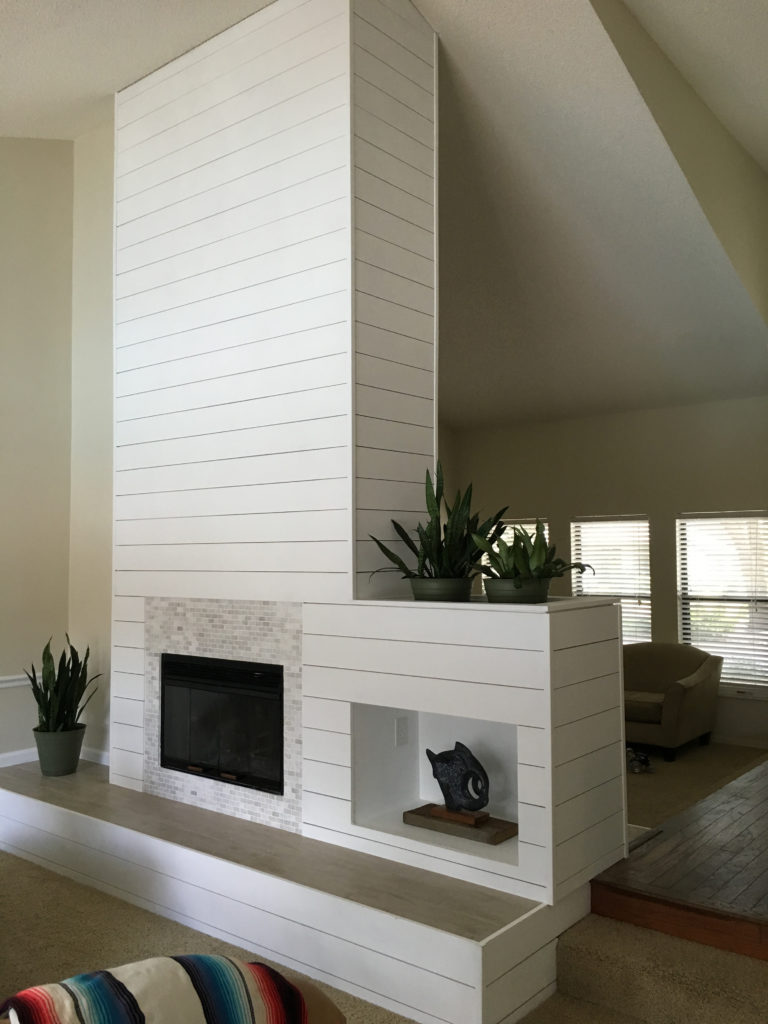 Complete double-sided fireplace with shiplap, wood look tile on the hearth, and marble subway tile surround